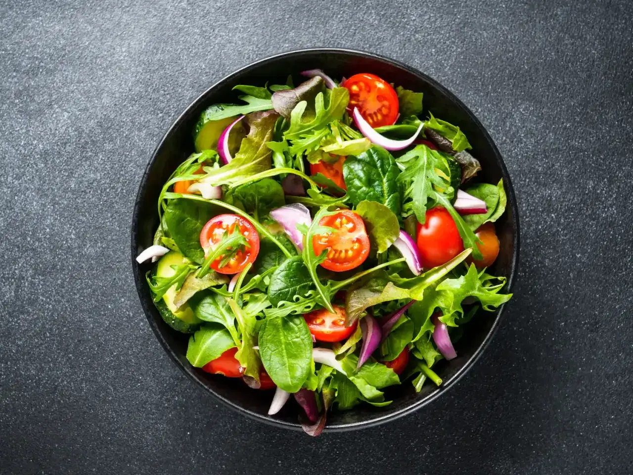 Salade fraîche et colorée avec tomates cerises, concombres et oignons rouges. Un délice pour savoir comment conserver la salade.