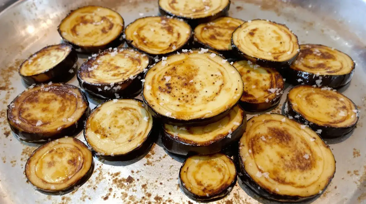 Rondes tranches d'aubergines grillées au four, parsemées de gros sel, prêtes à être dégustées.