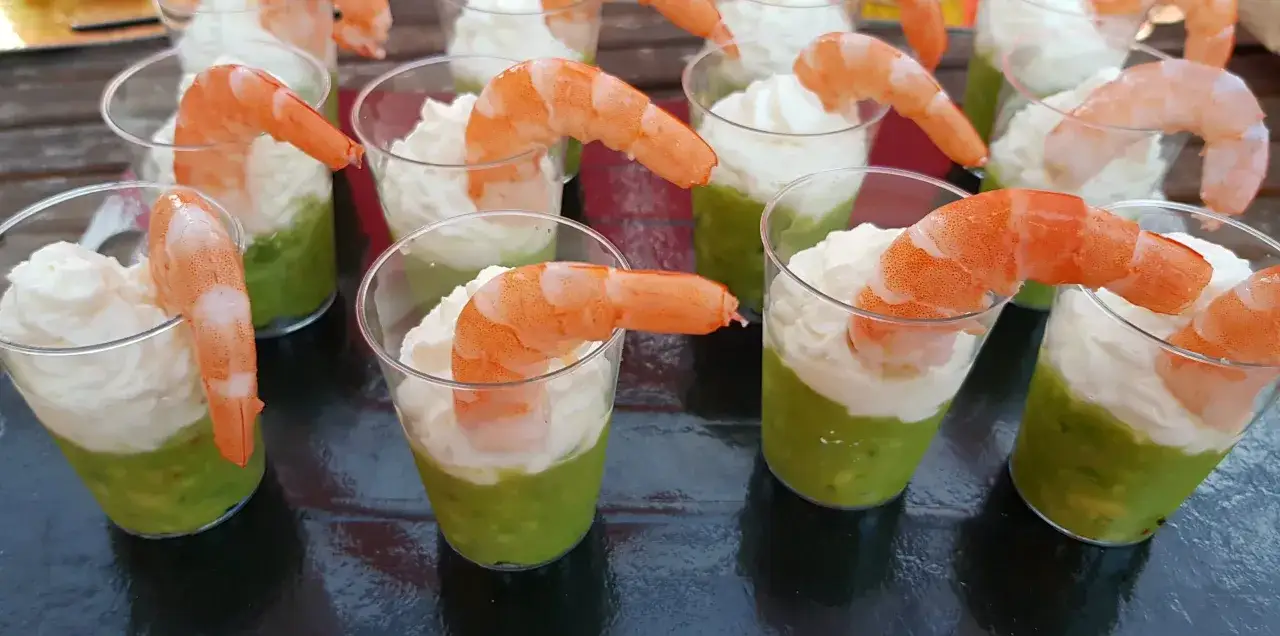 Verrines avocat crevettes : une couche d'avocat écrasé surmontée d'une mousse légère, décorée d'une crevette rose. Parfait pour un apéritif frais et coloré.