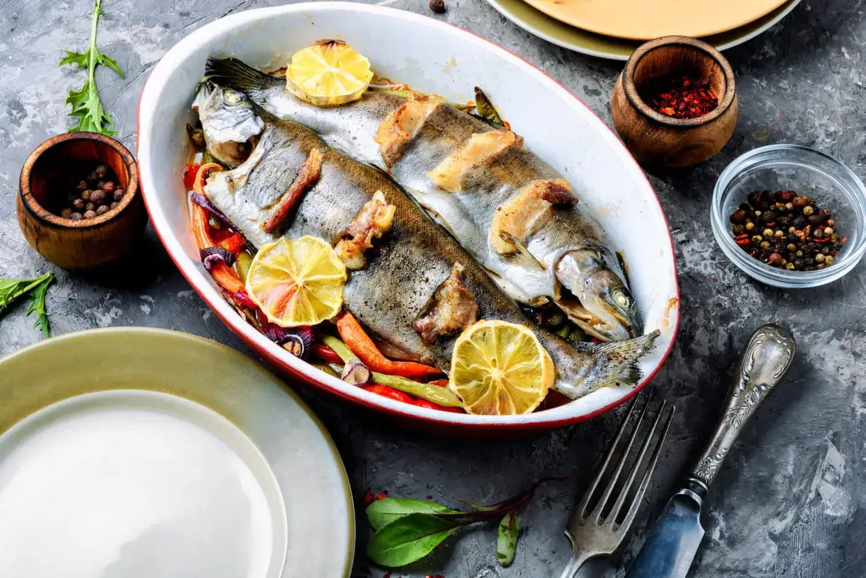 Deux truites entières, garnies de rondelles de citron et de légumes, sont prêtes à être dégustées. Un plat savoureux de truite en papillote.