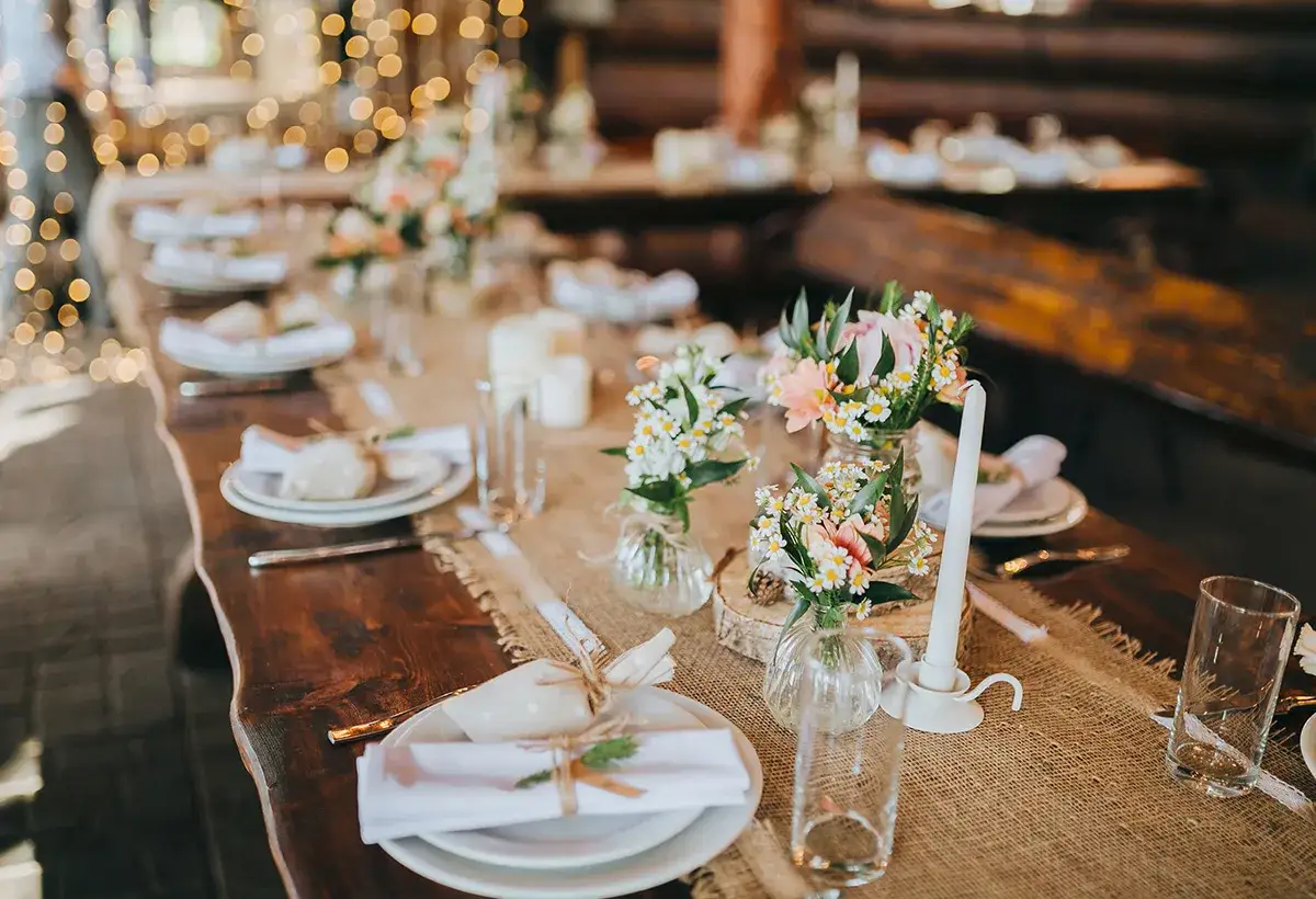 Table dressée pour un mariage rustique, avec des fleurs, des bougies et des sets de table en toile de jute. Idéal pour un budget mariage 30 personnes.