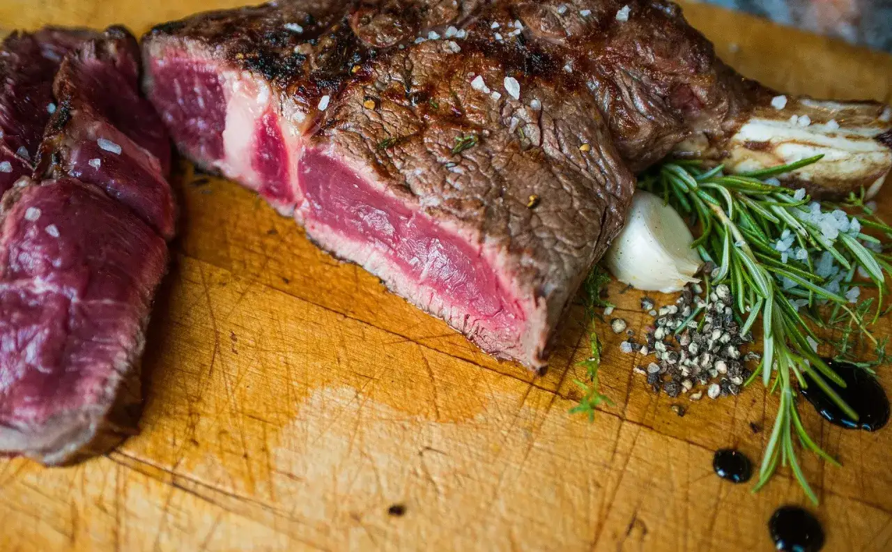 Un succulent bbq côte de boeuf, saignant et parsemé de gros sel, prêt à être dégusté avec des herbes fraîches et de l'ail.