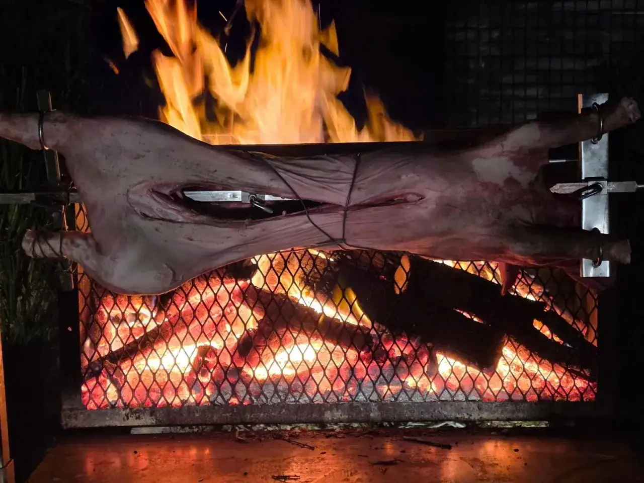 Un cochon à la broche tourne lentement au-dessus d'un feu de bois ardent, promettant un festin savoureux.