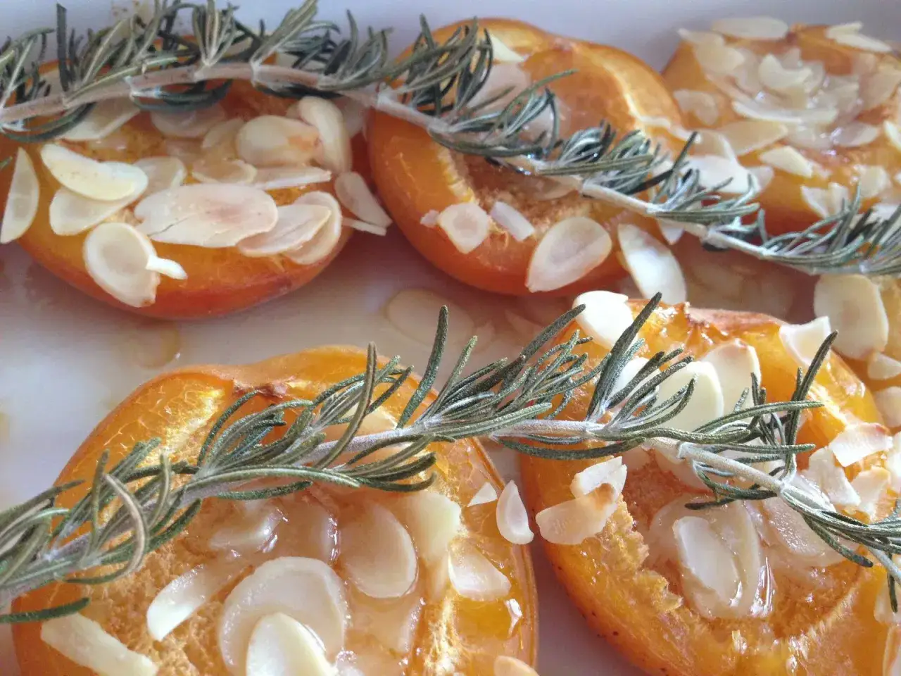 Abricots r&ocirc;tis au four, garnis d'amandes effil&eacute;es et d'une touche de romarin frais. Un d&eacute;lice sucr&eacute; et parfum&eacute;.