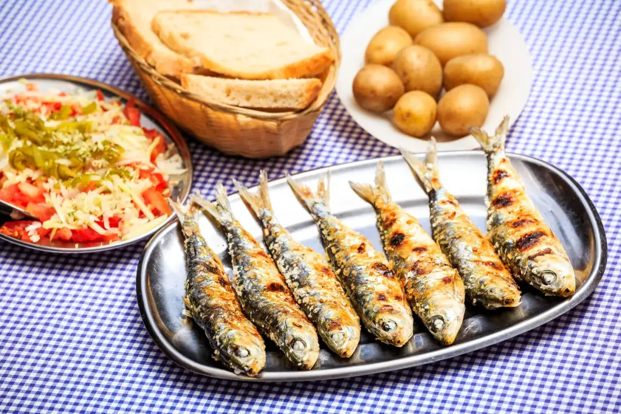 Sardines grillées sur un plateau, accompagnées de pommes de terre, salade et pain. La cuisson des sardines sans odeur est un vrai délice !
