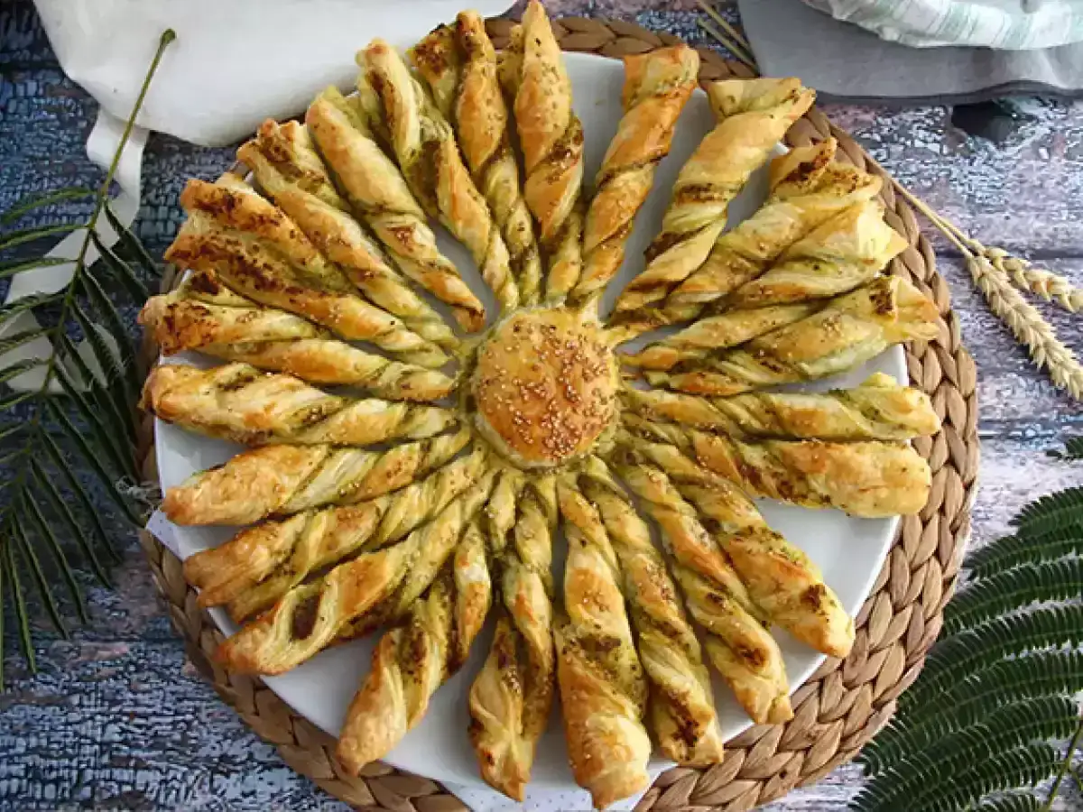 Une délicieuse tarte soleil pesto, aux rayons dorés et torsadés, parsemée de graines de sésame. Parfait pour un apéritif ensoleillé.