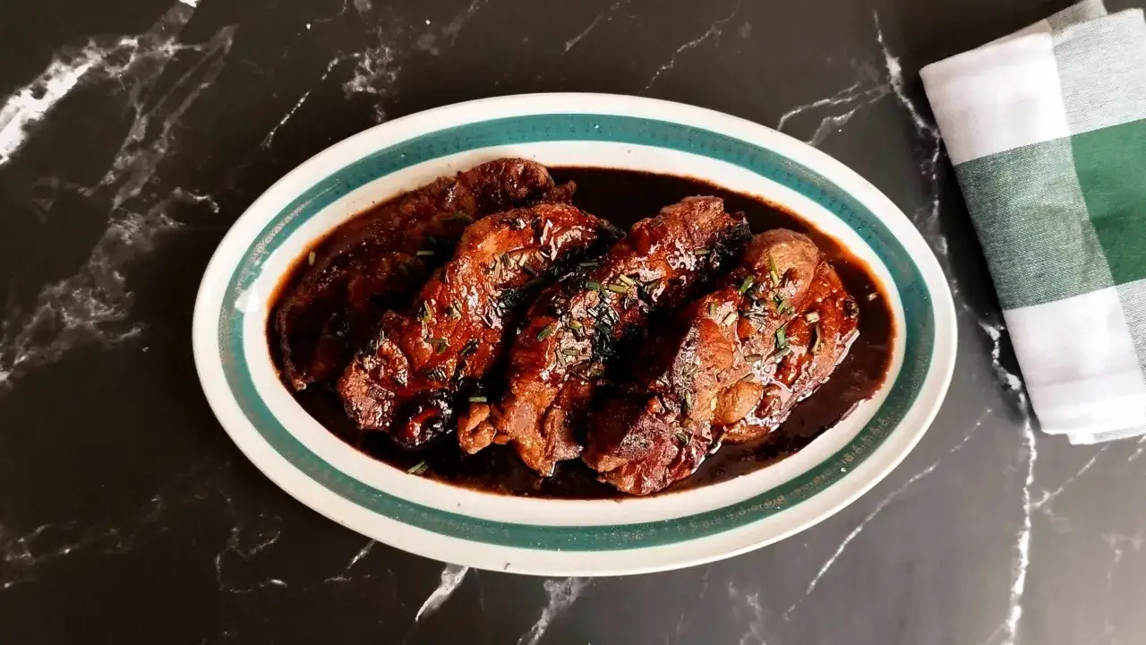 Quatre côtes de porc nappées d'une sauce brune savoureuse, garnies d'herbes fraîches. Un plat de côte de porc sauce soja prêt à être dégusté.