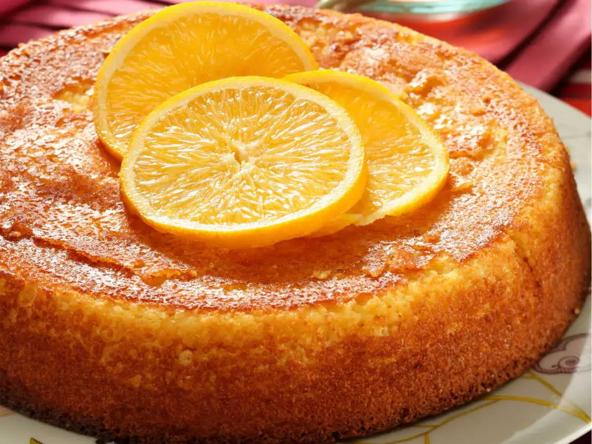 Un gâteau semoule orange moelleux, doré et garni de fines tranches d'orange, promet un délice fruité et léger.