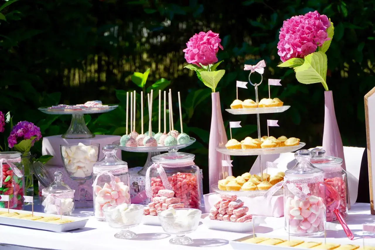 Buffet d'anniversaire fille 1 an : bonbons roses, cupcakes, cake pops et fleurs roses pour une fête magique.