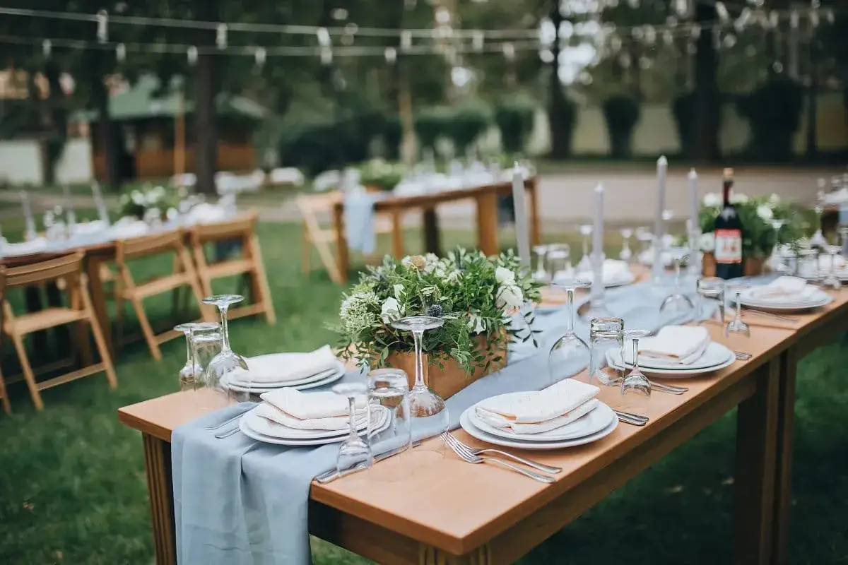 Tables dressées pour un mariage pique-nique en plein air, avec des fleurs, des bougies et des verres à pied.