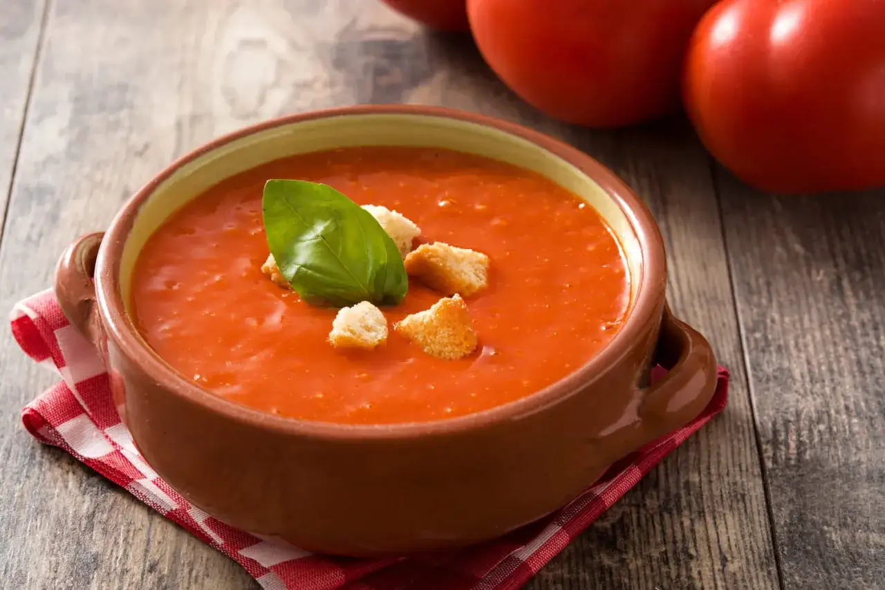 Soupe de tomates maison, garnie de cro&ucirc;tons et d'une feuille de basilic. Parfait pour savoir que faire avec des tomates trop mures.