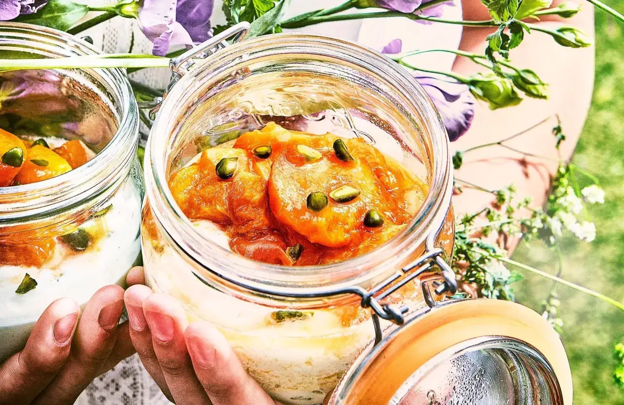 Délicieux dessert d'août en pot : fruits confits, crème onctueuse et pistaches croquantes. Parfait pour une pause gourmande ensoleillée.