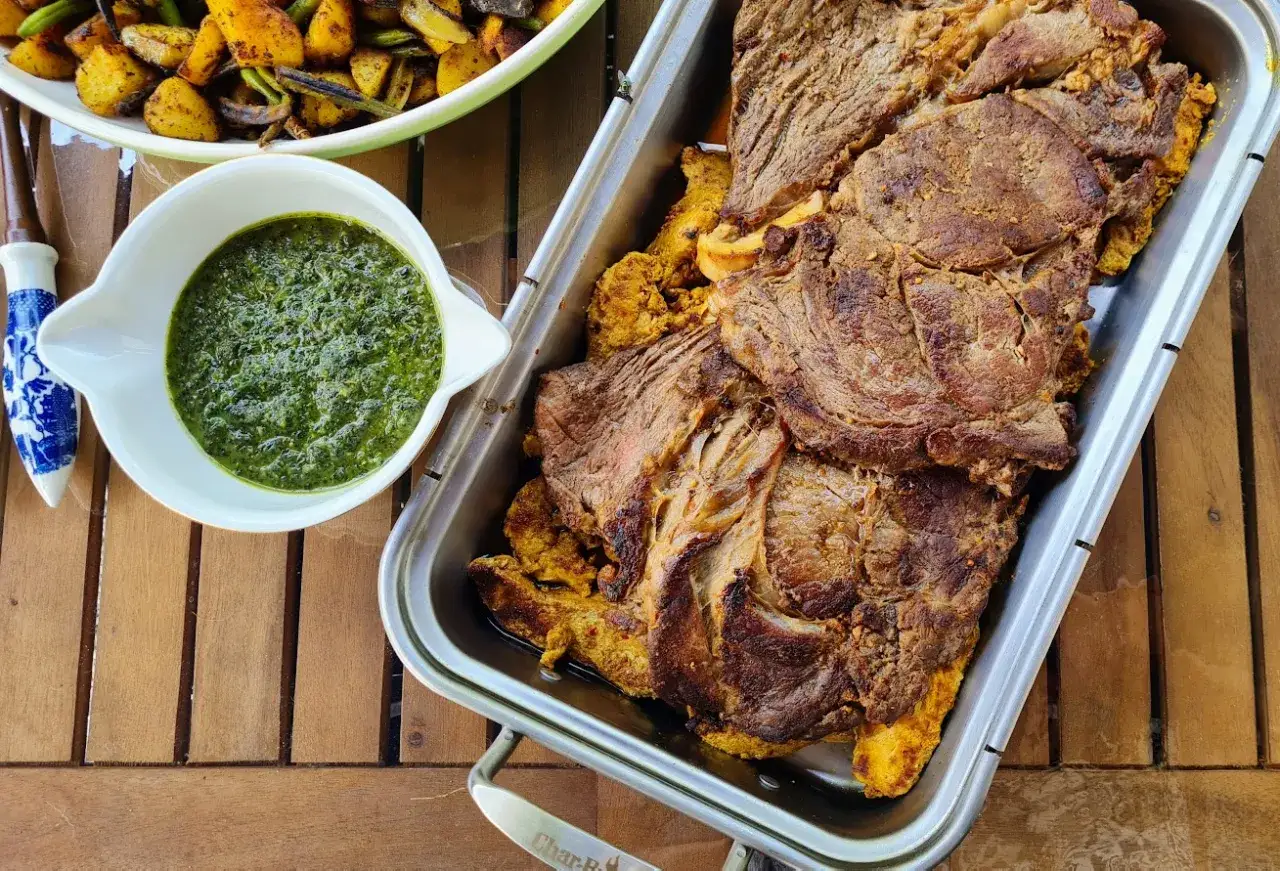 Basse côte juteuse, marinée pour un barbecue savoureux, accompagnée d'une sauce verte et de pommes de terre rôties.