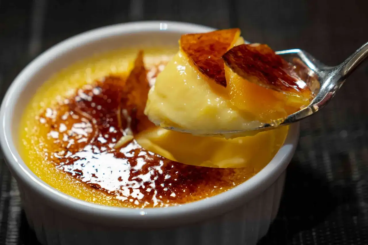 Une cuillère de crème brûlée, parfaite pour savoir que faire avec 5 jaunes d'œufs. La croûte caramélisée craque sous la cuillère.