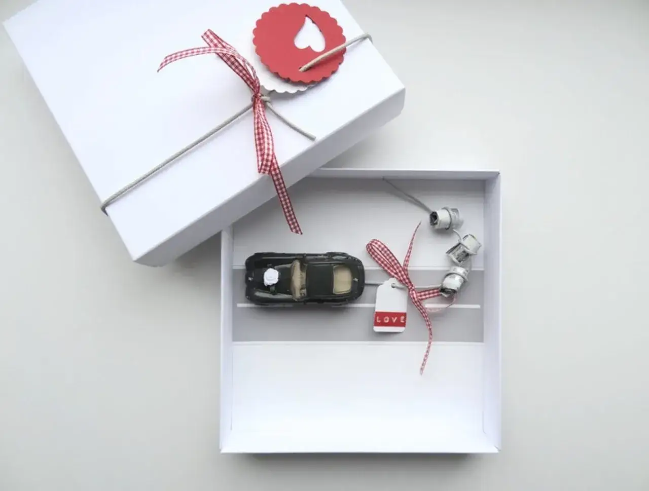 Une bo&icirc;te blanche ouverte r&eacute;v&egrave;le une petite voiture noire, des rouleaux de fil et une &eacute;tiquette 