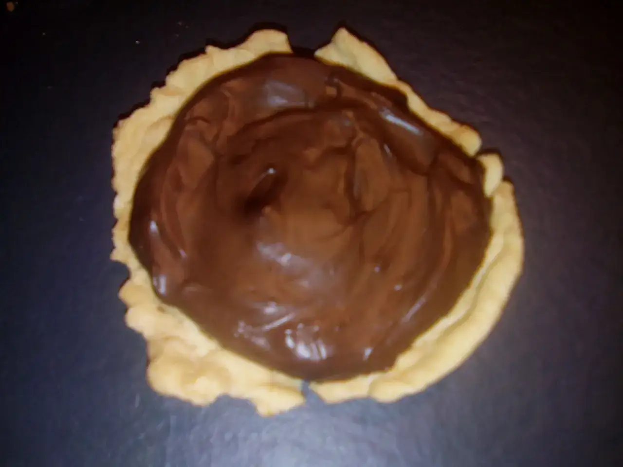 Une petite tartelette garnie de pâte à tartiner au chocolat. Parfait pour savoir que faire avec un reste de pâte brisée !