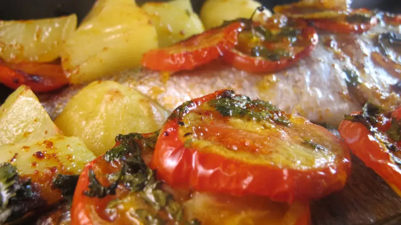 Dorade au four portugaise avec pommes de terre et tomates rôties, un plat savoureux et coloré.