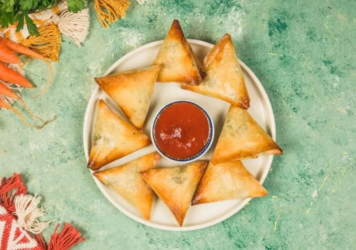 Assiette de samoussas boeuf oriental dorés, accompagnés d'une sauce tomate épicée. Parfait pour un apéritif savoureux.