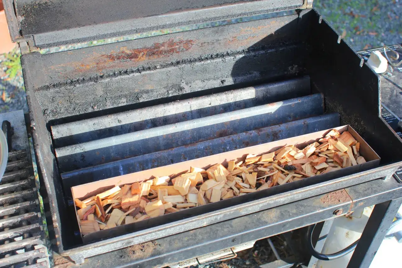 Boîte remplie de copeaux de bois dans un barbecue, prêt à fabriquer un fumoir.