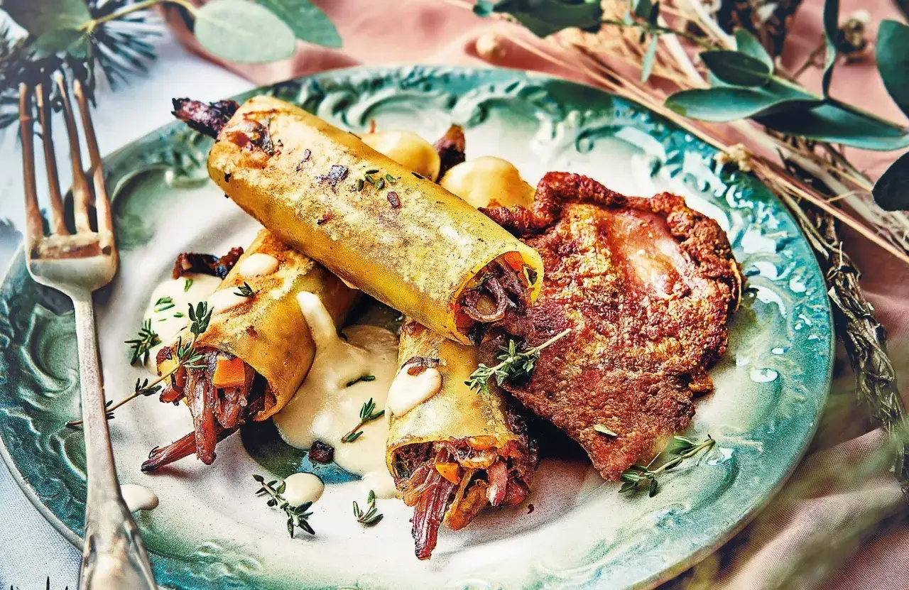 D&eacute;licieuse recette gourmande sal&eacute;e : cannellonis farcis &agrave; la viande et l&eacute;gumes, napp&eacute;s d'une sauce cr&eacute;meuse, accompagn&eacute;s d'une pi&egrave;ce de viande croustillante.