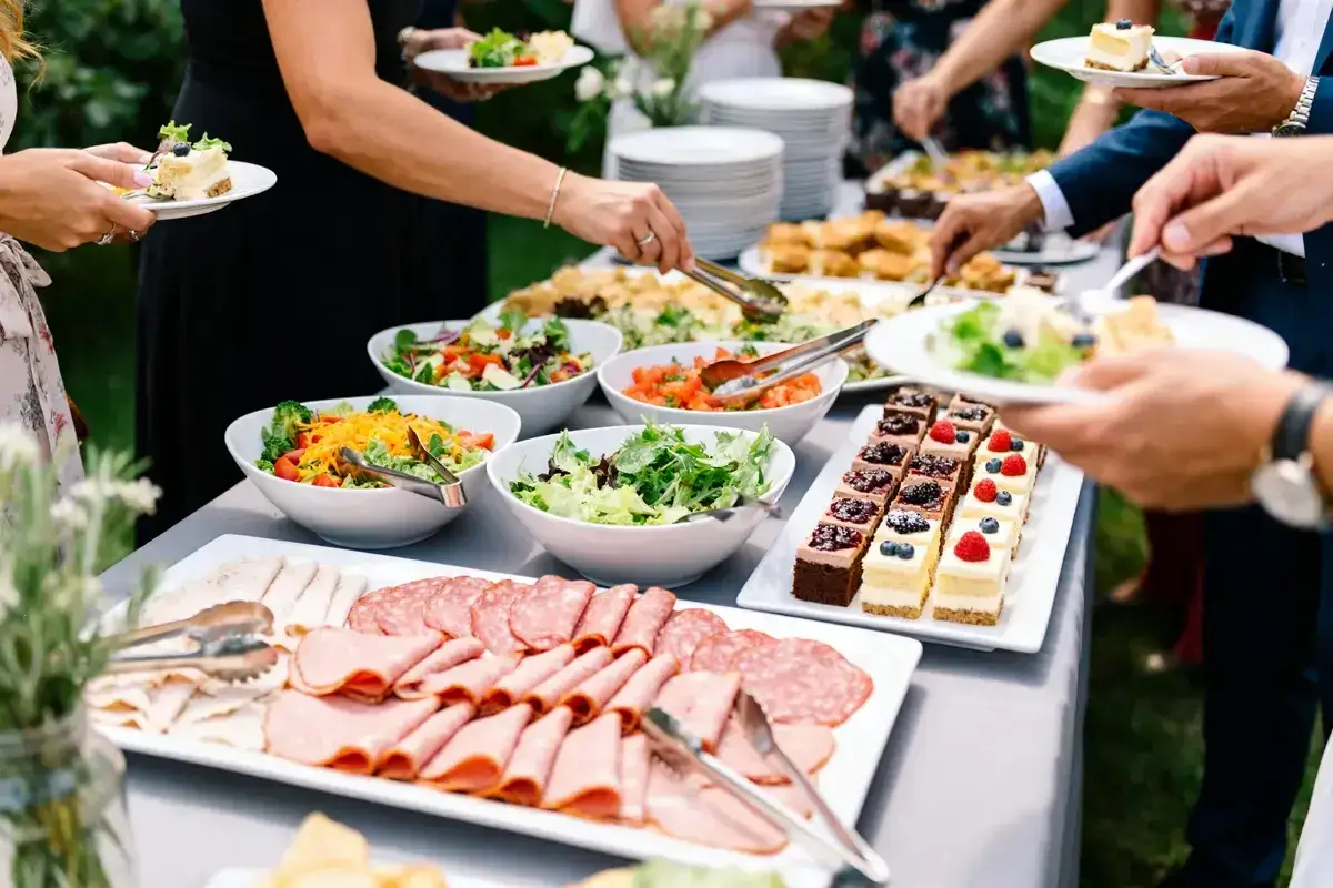 Buffet de mariage avec charcuterie, salades et petits gâteaux. Parfait pour un repas froid en plein air.