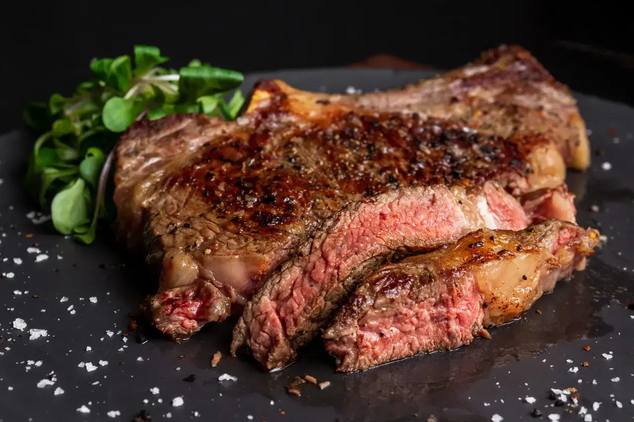 Un steak saignant, coupé en tranches, avec une garniture de salade verte. Le secret pour savoir quand saler la viande au barbecue est dans la cuisson parfaite.