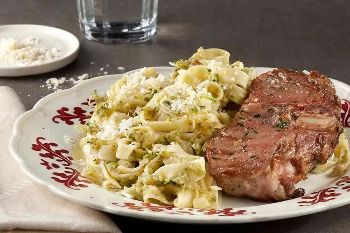 Délicieuse côtelette d'agneau grillée avec un accompagnement de pâtes crémeuses et de parmesan râpé.