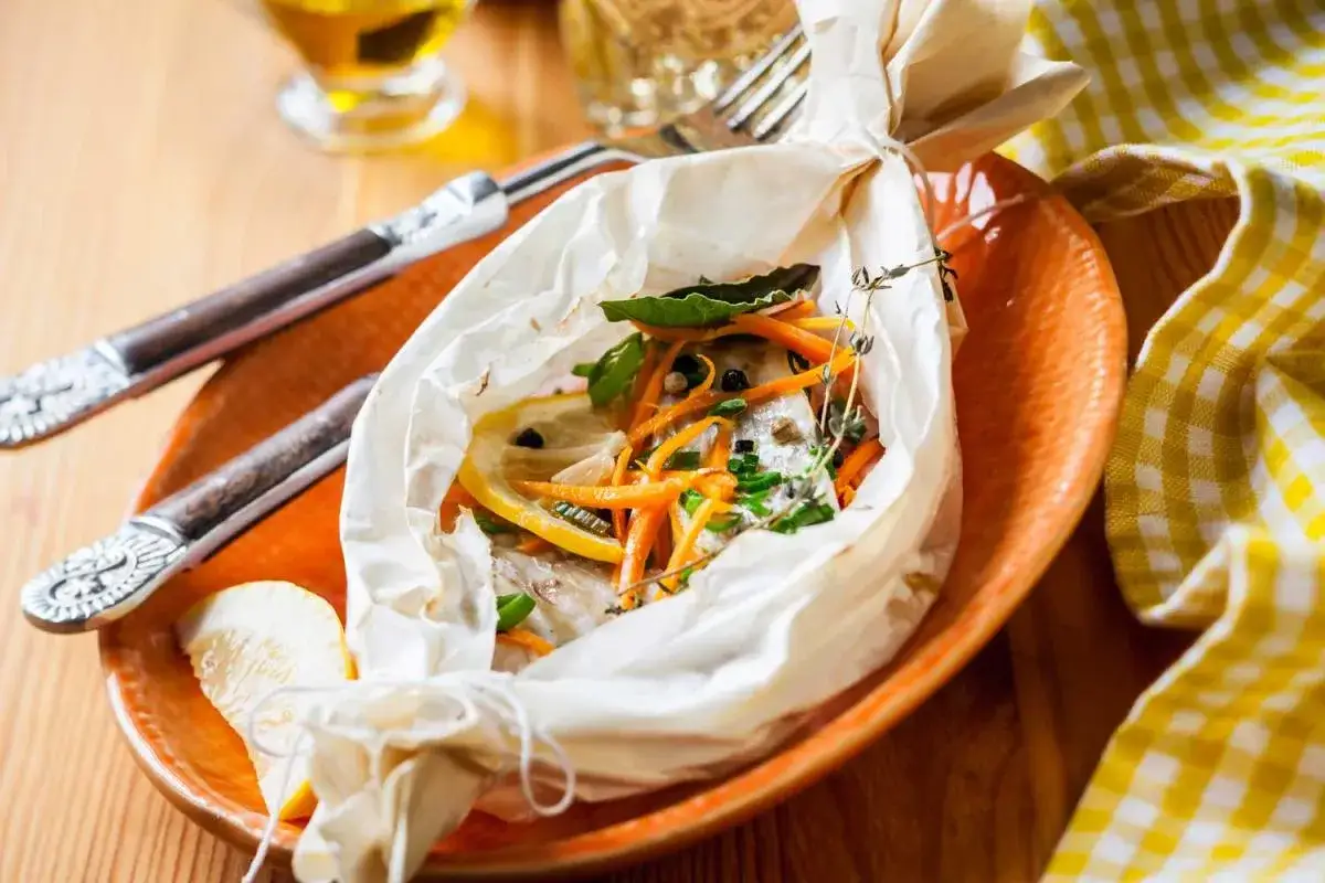 Dos de cabillaud en papillote, prêt à cuire avec carottes, citron et herbes. Le temps de cuisson idéal pour ce plat savoureux.