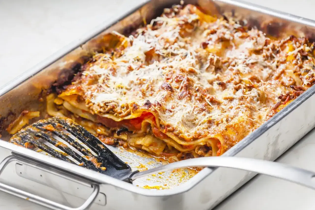 Lasagne maison dorée, un délice digne d'une recette lasagne chef italien. Une spatule attend patiemment de servir cette merveille.