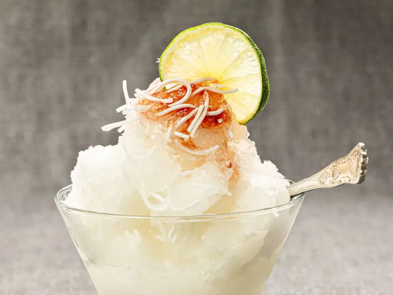 Un délicieux dessert iranien glacé, garni de copeaux de noix de coco et d'une tranche de citron vert.