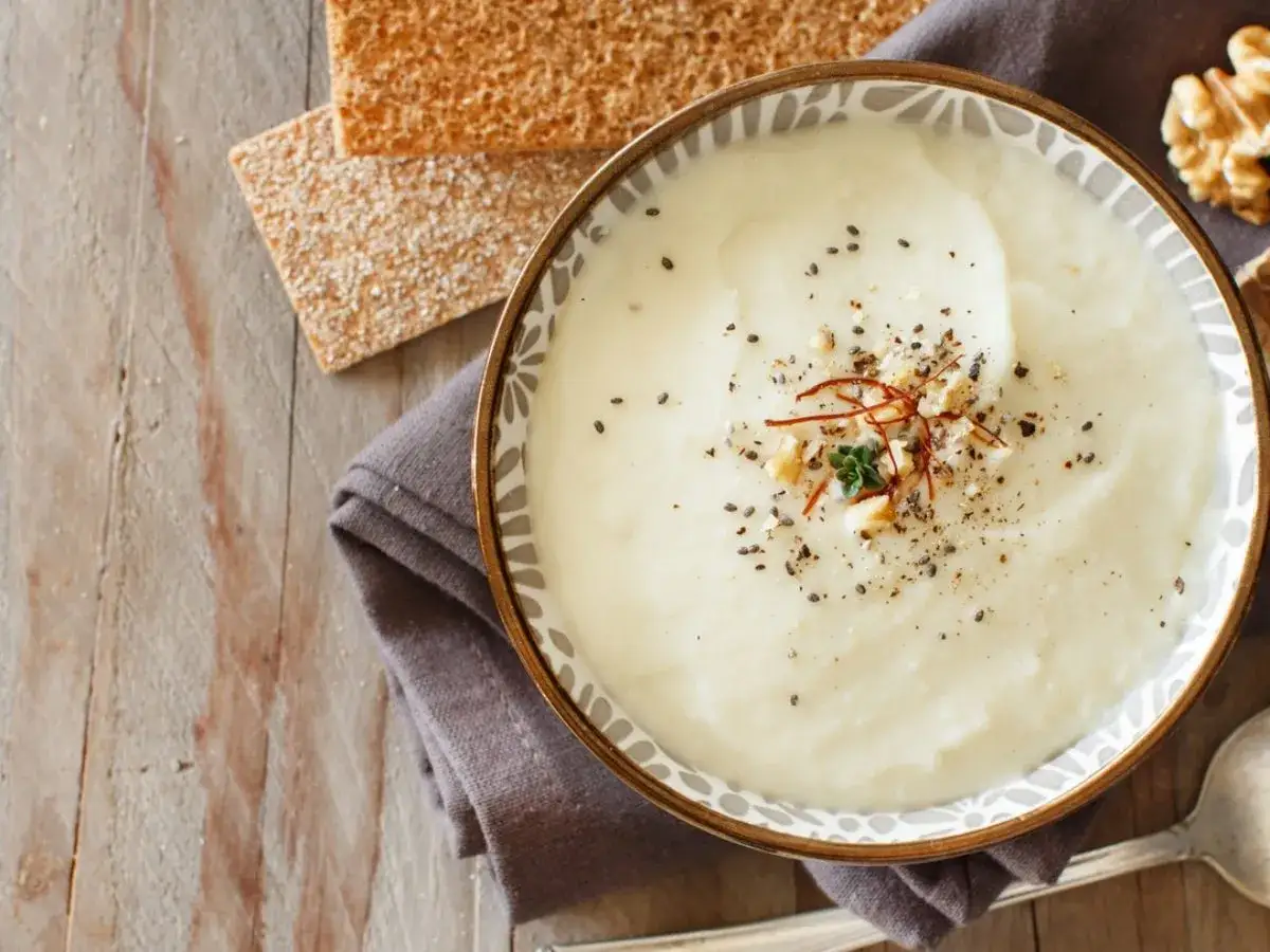 Velouté crémeux de reste de choux fleur cuit, garni de graines de sésame, noix et safran. Servi avec des crackers.