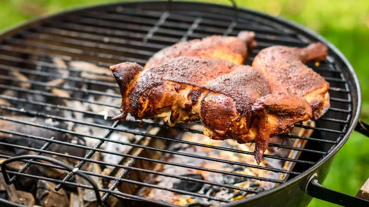 Trois cuisses de poulet au barbecue charbon, dorées et juteuses, grésillent sur la grille. La fumée s'échappe, promettant un délice savoureux.