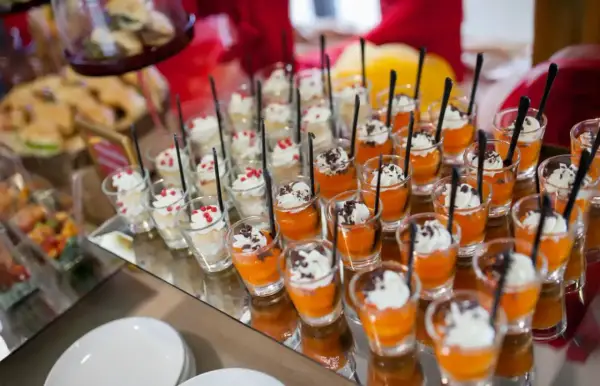 Petits desserts individuels en verrines, certains à la crème et fruits rouges, d'autres à la mousse orange et copeaux de chocolat. Un nom de menu original serait parfait pour ces délices.